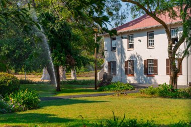 Güney Afrika 'da, stellenbosch' ta bir ev binasının önündeki yeşil çimlerin sulanması ya da sulanması. Süslü bir koloni evinin önünde yeşil çimenler otomatik olarak sulanıyor..
