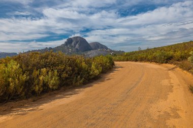 Güney Afrika 'daki Paarl şehrinin üzerindeki Paarl Dağı Doğa Koruma Alanı panoraması. Görünür göl ve büyük yuvarlak granit kaya oluşumlarının hakim olduğu fynbos bitki örtüsüyle bulutlu bir gün..
