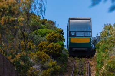 Funicular tren yolu bir uçurumun tepesindeki Cape Point deniz fenerine doğru gidiyor. Güney Afrika 'daki destansı noktaya hafif demiryolu asansörü, güneşli bir gün..