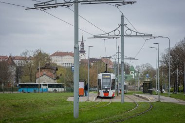 Tallinn 'deki modern bir tramvay bulutlu bir gökyüzünün altındaki yeşil bir alanda yol alır. Tarihi binalar, bir otobüs ve bir tramvay durağı görülebiliyor, arka planda Alexander Nevsky Katedrali, eski ve yeni ile harmanlanmış...