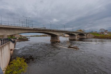 Narva, Estonya 'daki dostluk köprüsü. Narva Nehri boyunca uzanır ve Estonya ile Rusya 'yı birbirine bağlar. Katı beton kemerler ve elektrik direkleriyle bulutlu bir gökyüzü altında hem araçlara hem de yayalara hizmet eder..