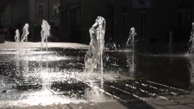 Şehir merkezindeki sakin bir şehir meydanında, yağmurlu kaldırımlarda parıldayan yansımalarla şehir fıskiyeleri güneş ışığına çıkar. Avrupa 'da sakin bir sabah ya da öğleden sonra ortamı.