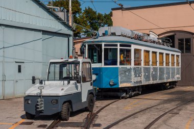 Eski Opicina tramvay sistemi Opicina tren istasyonunun yan raylarında yenileniyor, görünür turuncu perdeler ve tramvayın ön tarafındaki traktör kumla kaplanmış.