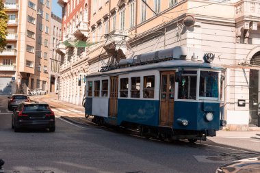 Klasik mavi Opicina tramvay 404 İtalya, Trieste 'deki Piazza Dalmazia' dan geçiyor. Tarihi binalar, arabalar ve yayalarla çevrili tramvay, kentin eşsiz ulaşım mirasını ön plana çıkarıyor..