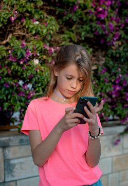girl using a smart phone in the street in a sunny summer day