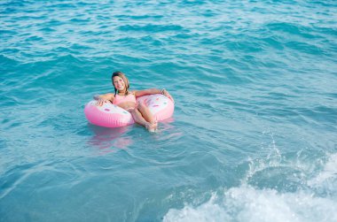 Beautiful young girl with inflatable ring relaxing in the sea
