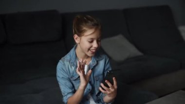 4k  girl hold smartphone, watching social media in modern living room.