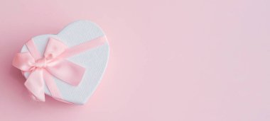 Aziz Valentine 'dan bir hediye. Pembe bir kalp ve pembe bir fiyonklu hediye kutusu. Romantik kart.