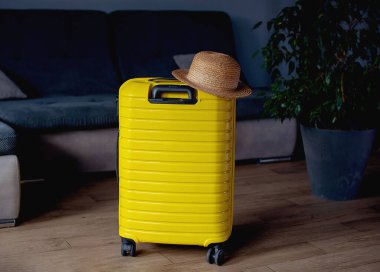 Yellow suitcase with hat . travel concept. minimal style