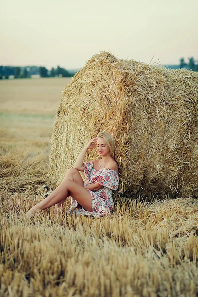 若い美しい女性は 干し草の上に閉じた目で座っています 田舎の休日 — ストック写真