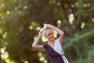 Close up image of happy blonde woman in sunglasses posing outdoors