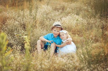 Children playing catch-up in the green field at sunset.