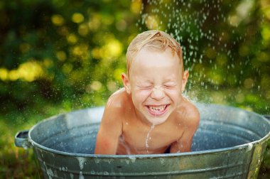 Summer vacation in countryside, local staycation. Happy little boy having fun to bath, selective focus