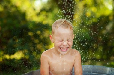 Happy little boy enjoying relaxing and splashing in water