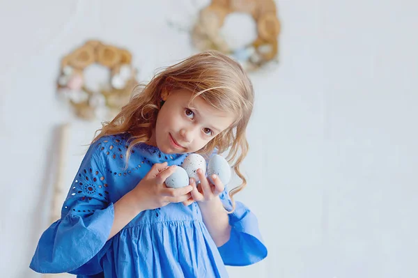 Portrait of lovely, cheerful blond girl , holding colored eggs, celebrating Easter with family