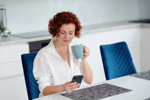 stock image Happy woman using mobile phone while working at home . Smiling woman messaging with smartphone. Beautiful lady browsing site on cellphone