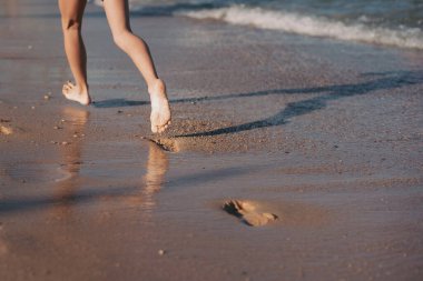 Dişi ayaklar deniz dalgasına basıyor. Yaz tatilleri konsepti