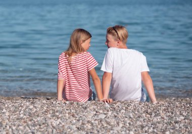 Kız ve erkek kardeşler sahilde.