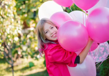 Yakından çekilmiş portresi. Güzel görünümlü, çekici, sevimli, sevimli, neşeli, neşeli, helyum topları dolu bir kız.