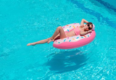 Sıcak yaz gününde, açık havuzda renkli şişme yüzükle oynayan mutlu kız. Çocuklar tropikal tatil köylerinde oynarlar. Aile plaj tatili