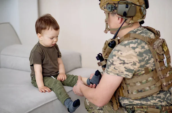 Askeri üniformalı Ukraynalı asker bir çocuğa yardım ediyor.
