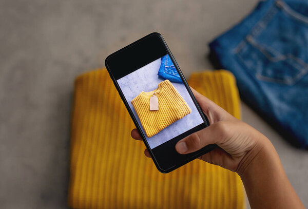 Женщина фотографирует рубашку на смартфоне