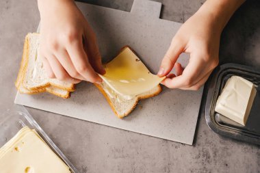 Eller sandviç yapıyor. Kahvaltı hazırlamak, tost ekmeğine peynir koymak..