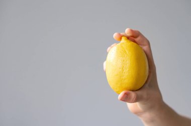 Vejetaryenler ve konunun doğası gereği taze meyve ve sebzeler: arka planda limon tutan insan eli