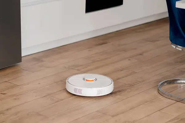 White robot vacuum cleaner washes the floor.