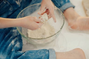 Küçük kız hamurla çalışıyor. Pizza yapmak ya da ev yapımı kurabiyeler. Karantina ve kendini tecrit sırasındaki dersler. El ve hamura yakın çekim