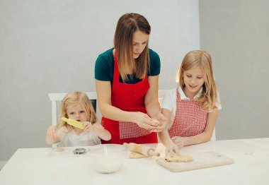 Anne ve kızları mutfakta kurabiye yapıyor ve evde eğleniyorlar.