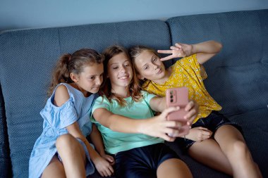 Çocuklar kanepede selfie çekiyorlar.