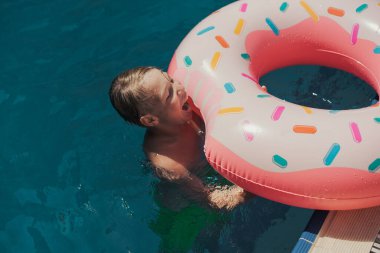 Çocuk yukarıdan şişme yüzükle havuzda yüzüyor