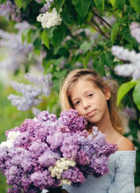 Bir buket leylakla güzel bir genç kız, leylak içinde bir kız, baharda leylaklar. Genç kız bir demet leylakla poz veriyor.