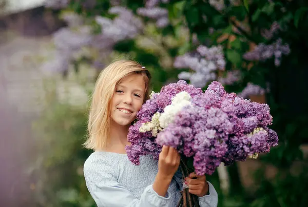 Bir buket leylakla güzel bir genç kız, leylak içinde bir kız, baharda leylaklar. Genç güzel esmer kız bir demet leylakla poz veriyor.