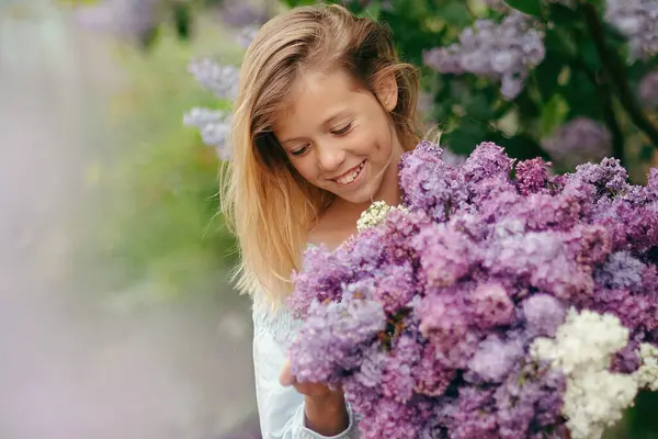 Bir buket leylakla güzel bir genç kız, leylak içinde bir kız, baharda leylaklar. Genç güzel esmer kız bir demet leylakla poz veriyor.