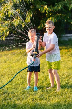 Mutlu Aile Bahçe Su Hortumuyla Oynuyor, Birbirlerine Sprey Spreyliyorlar. Aile, güneşli yaz gününde Idyllic Banliyö Evinin arka bahçesinde eğlenceli oyunlar oynar