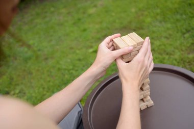 Kadın dikkatini bir masada tahta blok oyunu oynamaya, tahta bir bloğu hareket ettirmeye veriyor. Oyuncak, oyun, eğlence. dijital detoks