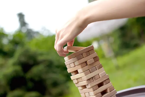 stock image Close up woman building tower from wooden blocks , playing game, sitting at table