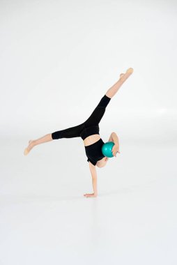 ritmik jimnastikçi topla performans sergiliyor, yeteneklerini gösteriyor ve beyaz arka planda yalnız kalıyor. Spor anlayışı, aktif yaşam tarzı, hobi.