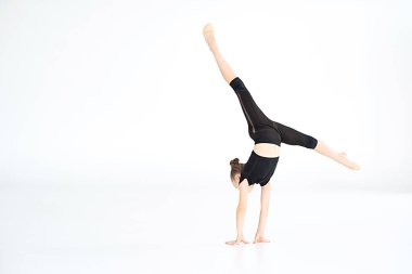 Beyaz arka planda izole edilmiş jimnastik egzersizleri yapan siyah mayo giymiş genç jimnastikçilerin portresi. Spor, beceri, başarı.