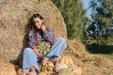 Balkabağı hasadı. Çiftlikte sonbahar sebze mahsulü toplayan portre kadın çiftçi. İşçiler büyük balkabağını tarlada tutuyor. Cadılar Bayramı. Şükran Günü