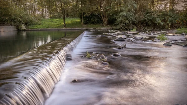 Mountain River şelalesi. Taş ve suyun güzel doğal arka planı. Uzun pozlama. Batan güneşin ışınlarında görülebilir nehir kıyısı. Boşluğu kopyala.