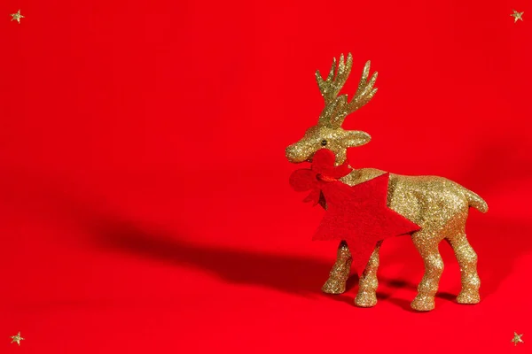 Kırmızı kumaşlı altın rengeyiği heykelciği. Noel arkaplanı / kartı, hediye kartı, kırmızı yıldız - kolye / etiket. Kopya alanı olan Noel duvar kâğıdı. 