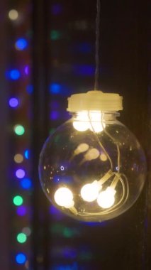 Mobil dikey çözünürlük 1080x1920 piksel. Ön planda ampul var. Arka planda renkli tatil ışıkları var. Kış aydınlatması yakın çekim. Bokeh ve odak dışı bakış. Parti için dekorasyon, Noel ya da yeni yıl için. 