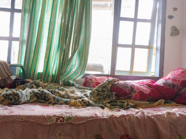 Yatak odası darmadağın. Dağınık bir yatak, yastıklar, destekçiler ve toparlanmamış yorganlar olan bir çocuk odası. Gerçek hayat..