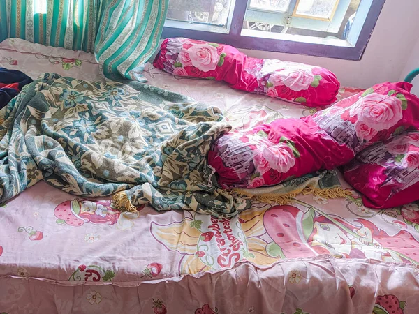 The bedroom is a mess. A child\'s room with a messy bed and pillows, bolsters and quilts that have not been tidied up. real life.