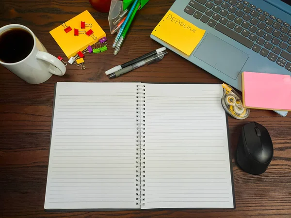 Flat lay, a mock up of a notebook. workspace in the background of the office desk from the top view. A workspace with white notebooks, laptops, office supplies, pencils, and coffee cups in the background of a wooden desk.