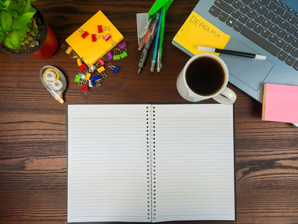 Flat lay, a mock up of a notebook. workspace in the background of the office desk from the top view. A workspace with white notebooks, laptops, office supplies, pencils, and coffee cups in the background of a wooden desk.