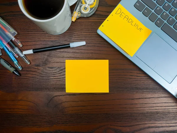 Flat lay, mock up yellow notes. workspace in the background of the office desk from the top view. A workspace with yellow notes, laptops, office supplies, pencils, and coffee cups in the background of a wooden table.